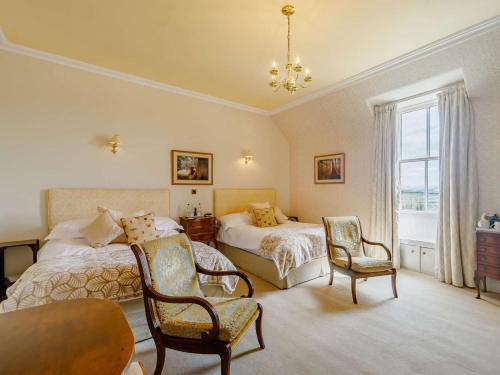 a bedroom with two beds and a table and chairs at 5 Bed in Melrose oc-89348 in Newtown Saint Boswells