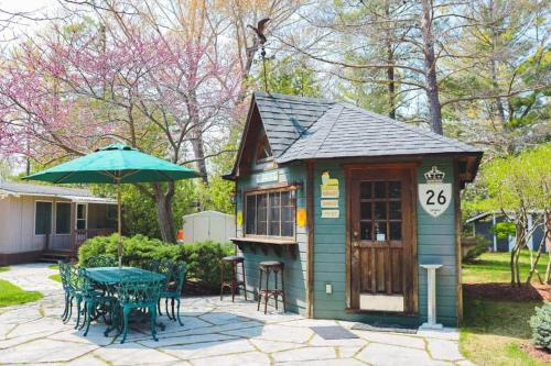 a smallshed with a table and chairs and an umbrella at Lighthouse at Evergreen Resort in WB in Wasaga Beach