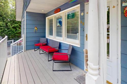 a porch with red chairs and a blue house at Wavy Daze in Wasaga Beach in Wasaga Beach