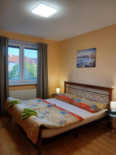 a bedroom with a large bed and two windows at Apartments Orange in Uherské Hradiště