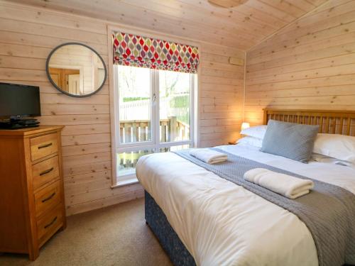 a bedroom with a bed and a television and a window at Dovestone Luxury Lodges sleeps 4- pet free in Oldham