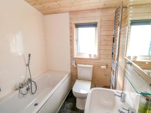 a bathroom with a tub and a toilet and a sink at Dovestone Luxury Lodges sleeps 4- pet free in Oldham