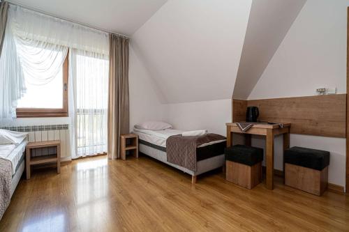 a bedroom with two beds and a desk and a window at Pokoje gościnne u Eli i Jacka in Murzasichle