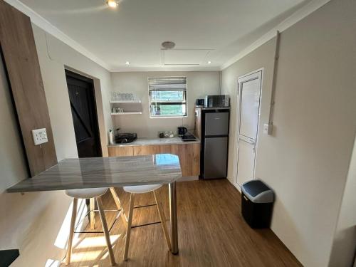 a small kitchen with a table and a refrigerator at Meerlust Cottage in Cape Town