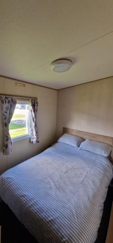 a bed in a small room with a window at Ty Mawr Summerbreeze in Kinmel Bay