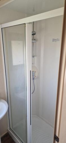 a shower with a glass door in a bathroom at Ty Mawr Summerbreeze in Kinmel Bay