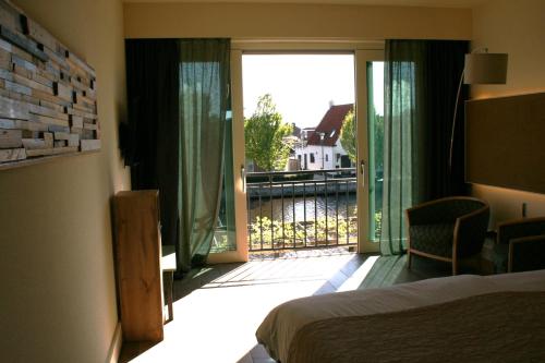 a bedroom with a bed and a view of a balcony at Hotel Noudus in Delfstrahuizen