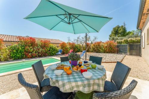 a table with a blue umbrella on a patio at Villa Santa - Piscine - Wifi - Proche Ventoux - idéal Cyclistes in Mormoiron