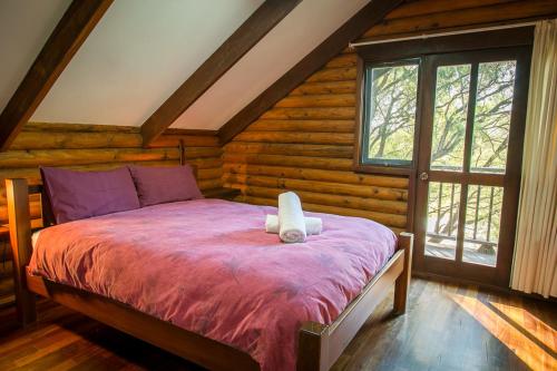 a bedroom with a bed in a log cabin at Wyadup Brook Cottages in Yallingup