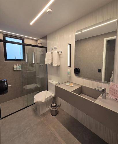 a bathroom with a shower and a toilet and a sink at H4 Hotel Opera Jardins in São Paulo