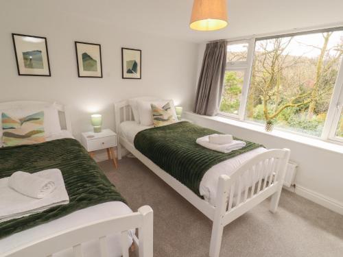 a white bedroom with two beds and a window at Rothay Cottage in Ambleside