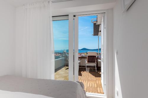 a bedroom with a bed and a balcony at Seaview Apartments Tihi II in Vodice