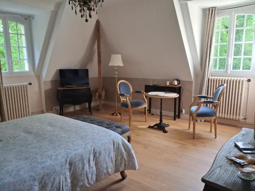a bedroom with a bed and a desk and chairs at Le Mesnil Landon in Lingèvres