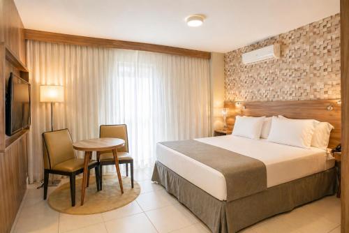 a hotel room with a bed and a table at Promenade Fusion Itaguaí in Itaguaí