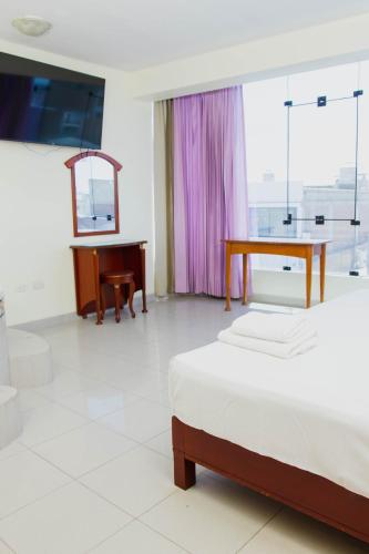 a bedroom with a bed and a desk and a table at Zentra San José Hotel & Cowork in Chiclayo
