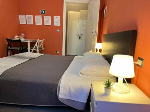 a bedroom with a bed and a table with a lamp at Adriatic Room 50 m dalla stazione Ferroviaria di Ciampino e dalla navetta aeroportuale in Ciampino