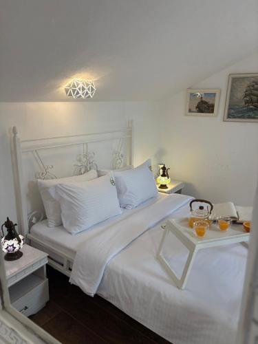 a white bed with white pillows and a table at Apartman Senka in Budva