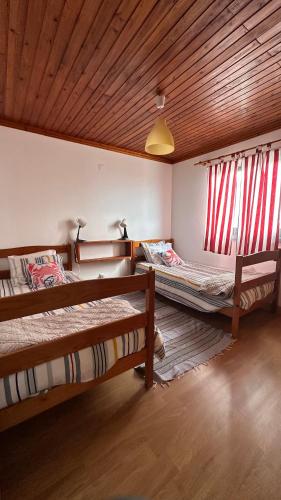 two beds in a room with red curtains at Longitude 31 House in Faja Grande