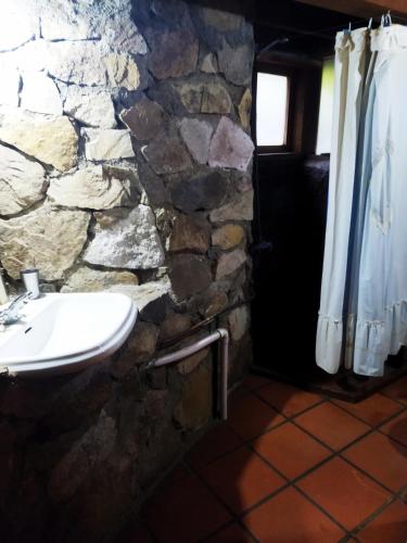 a stone bathroom with a sink and a stone wall at Hostal Nunatak in La Porteña