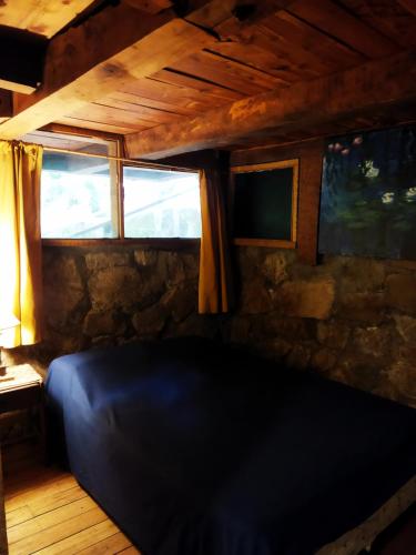 a black couch in a room with a stone wall at Hostal Nunatak in La Porteña