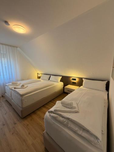 two beds in a hotel room with white sheets at FeWo Bispingen in Bispingen