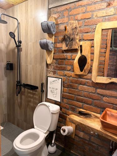 a bathroom with a toilet and a brick wall at Villa Rosa in Moshi