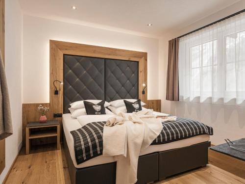 a bedroom with a large bed with a black headboard at Landhaus Mader Hintertux in Tux