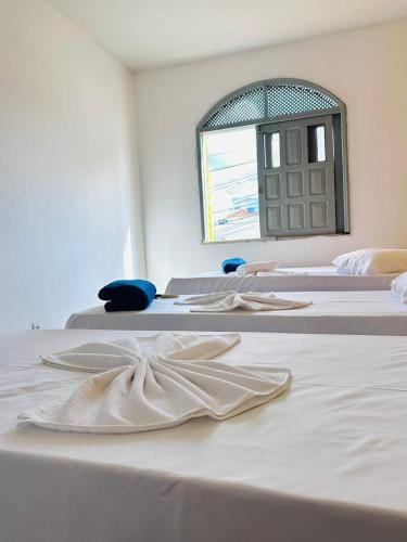 a white room with three beds and a window at Hotel Dairy Walley in Itapetinga