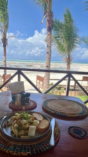 a table with a plate of food on the beach at Hekaya Zanzibar in Pingwe