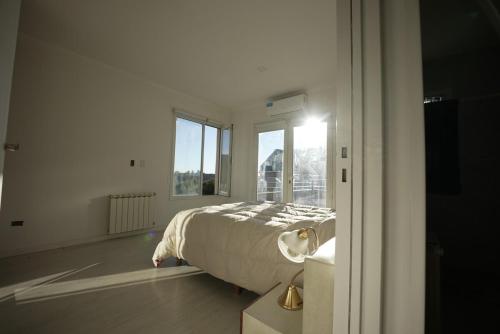 a white bedroom with a bed and a window at Casa Juanca in Comodoro Rivadavia