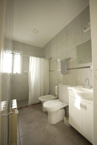 a white bathroom with a toilet and a sink at Casa Juanca in Comodoro Rivadavia