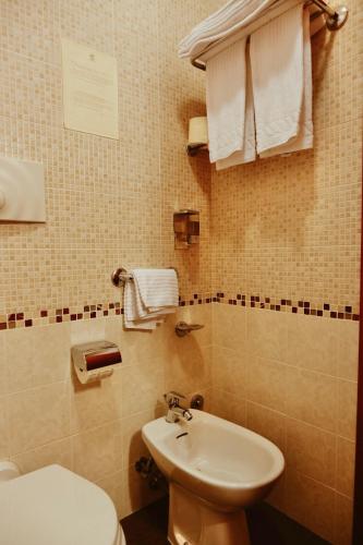 a bathroom with a sink and a toilet and towels at Hotel Ramapendula in Alberobello