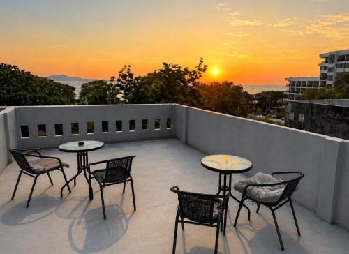 a patio with tables and chairs on a balcony with the sunset at Hostel Friends Station & Cafe in Pattaya South