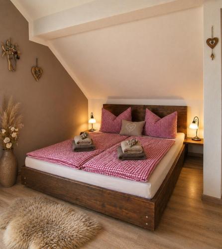 a bedroom with a large bed with pink pillows at Ferienwohnung Weber Alpenveilchen in Lechbruck