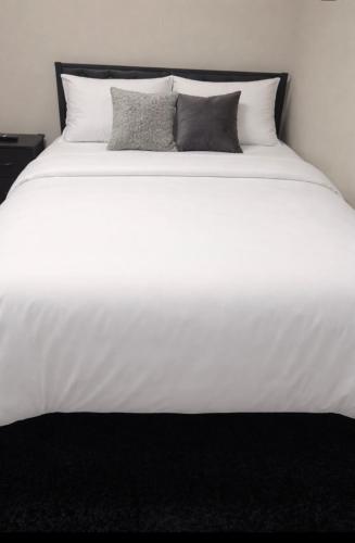 a white bed with two pillows on top of it at Anne room A in Irvington