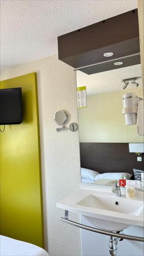 a bathroom with a sink and a bed at Cit'Hotel Primo Colmar Centre in Colmar