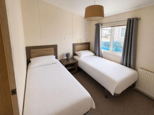 two beds in a small room with a window at Seaview Holiday Rentals - Pebble Beach in Whitstable