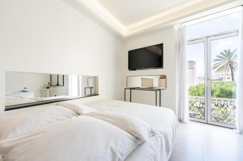 a white bedroom with a bed and a large window at Suite luxe jacuzzi - CANNES SUQUET in Cannes