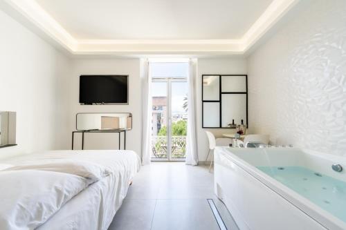 a white bedroom with a tub and a tv at Suite luxe jacuzzi - CANNES SUQUET in Cannes