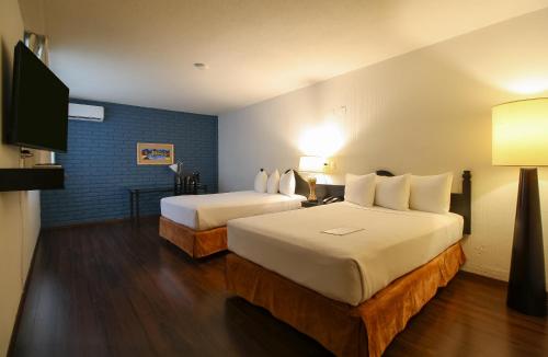 a hotel room with two beds and a flat screen tv at Hotel Casino Morelia in Morelia