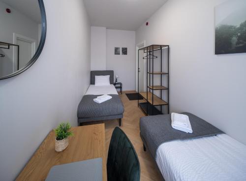 a room with two beds and a table and a mirror at M6 Rooms Riga in Riga