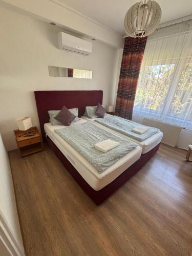 a bedroom with a large bed and a large window at Anonymus Vendégház in Siófok