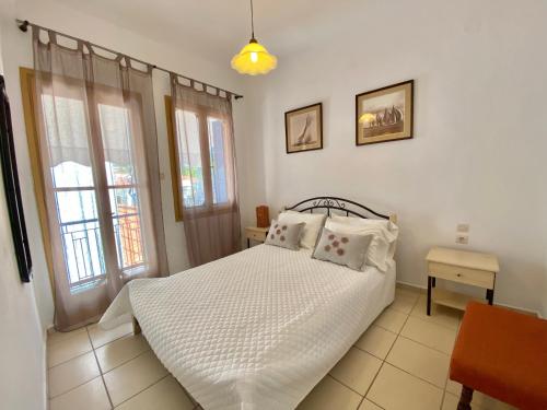a bedroom with a white bed and two windows at Ravanos Apartment in Loutraki