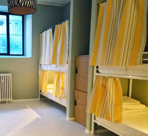 a room with two bunk beds with yellow curtains at Zippy Hostel in Milan