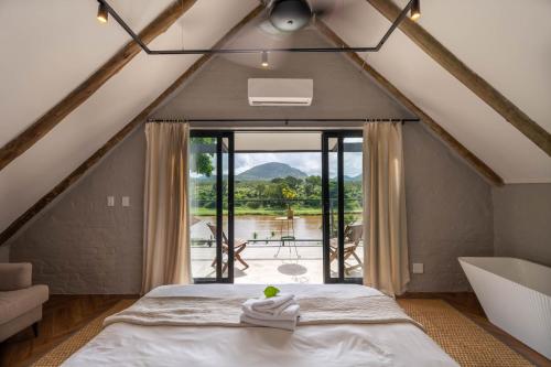 a bedroom with a bed and a large window at River House Lodge in Malelane