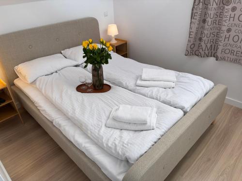 a bed with a vase with flowers on it at Mierzeja Bliss Point - Basen, Parking, Grill in Sztutowo
