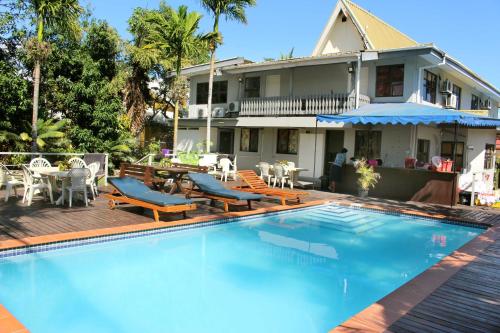 a swimming pool with chairs and tables and a house at Bluewater Lodge in Nadi