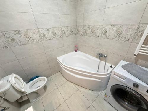 a bathroom with a tub and a toilet and a washing machine at RC RelaxApart 602 in Dudu