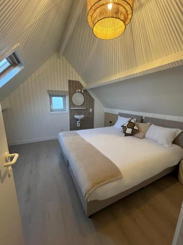 a bedroom with a large bed with a ceiling at Seaward Cottage met Jacuzzi in De Haan