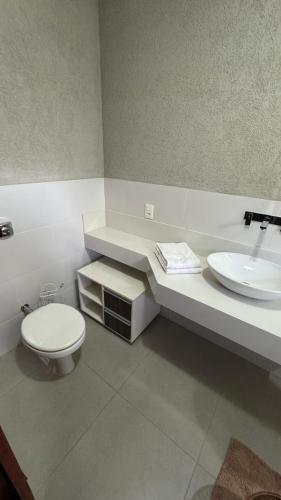 a bathroom with a toilet and a sink at Chácara com Piscina, Hidro, Campo de futebol, Beach Tennis, Sinuca e Churrasqueira in Analândia